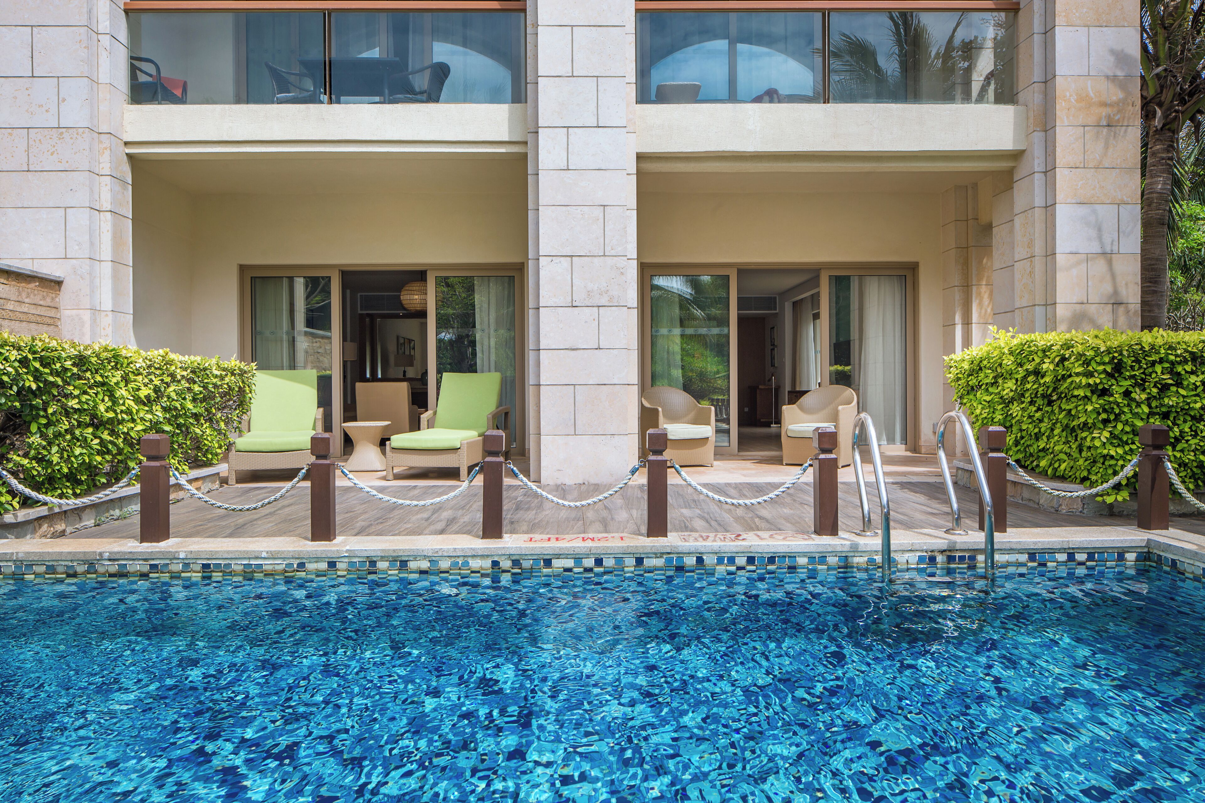 A pool area with lounge chairs and a clear view of the building's exterior.