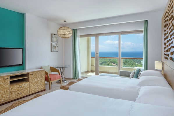 Habitación de hotel con una cama grande, televisión, escritorio y balcón con vistas.
