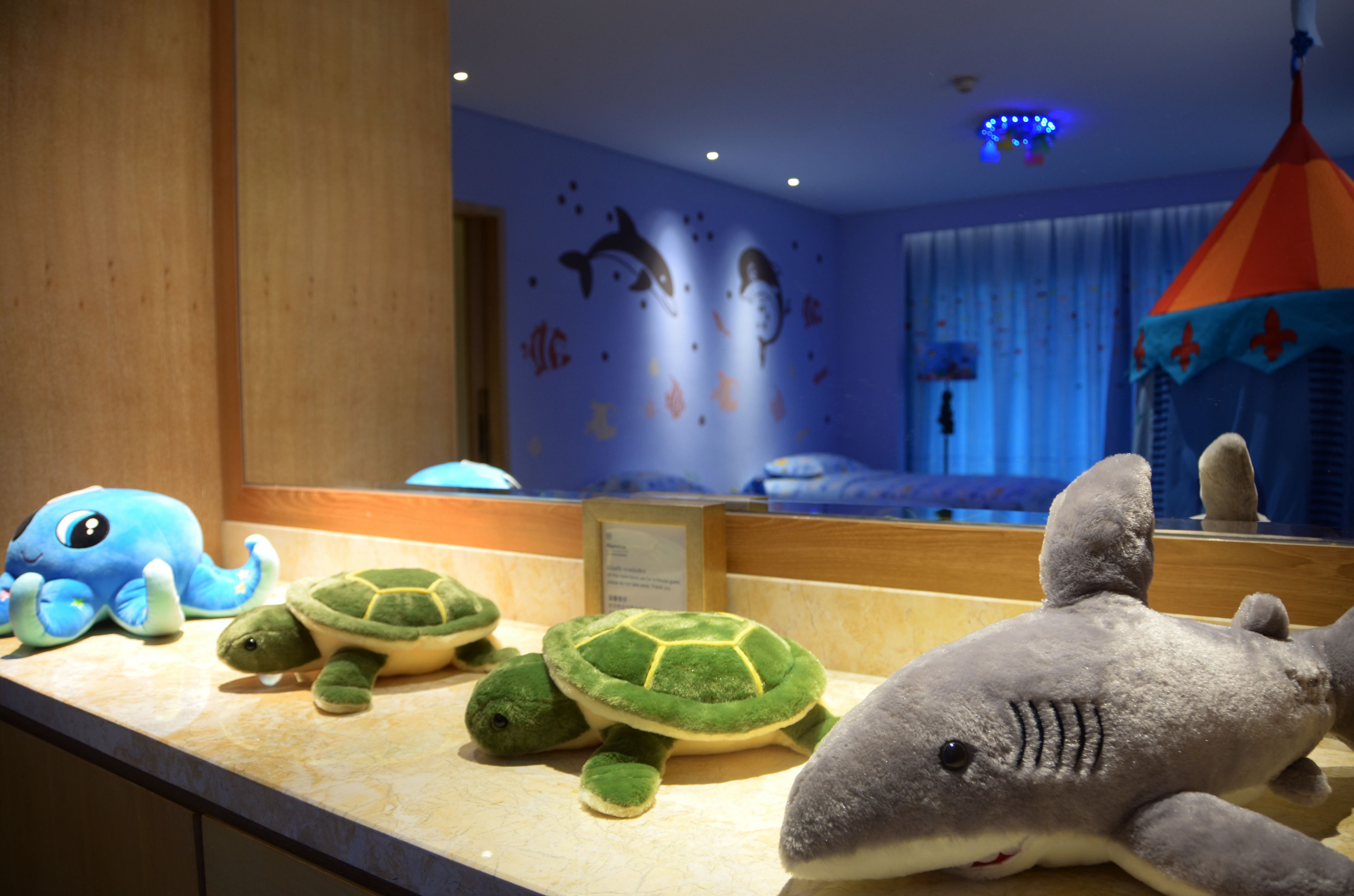 Plush toys on a counter, a bed with a canopy, and a wall with marine animal decals.