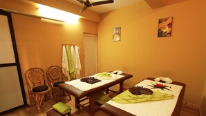 A room with two massage tables, a ceiling fan, and a door.