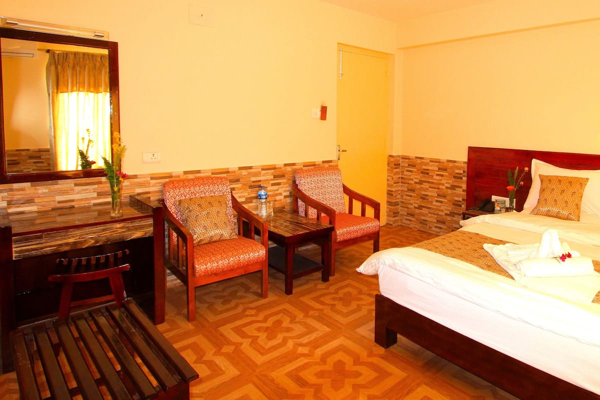 A hotel room with a bed, a desk, and two chairs.