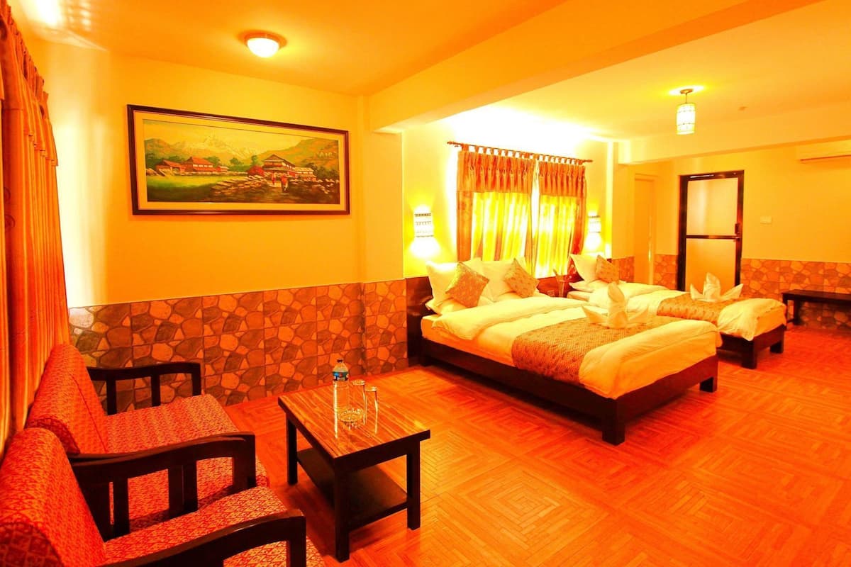 A hotel room with a bed, two chairs, a small table, a painting on the wall, and a window with curtains.