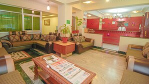 A hotel lobby with sofas, a coffee table, and a reception desk.
