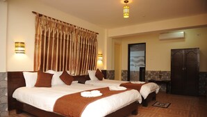 A hotel room with two large beds, a stone accent wall, a wardrobe, and a bathroom with a shower.