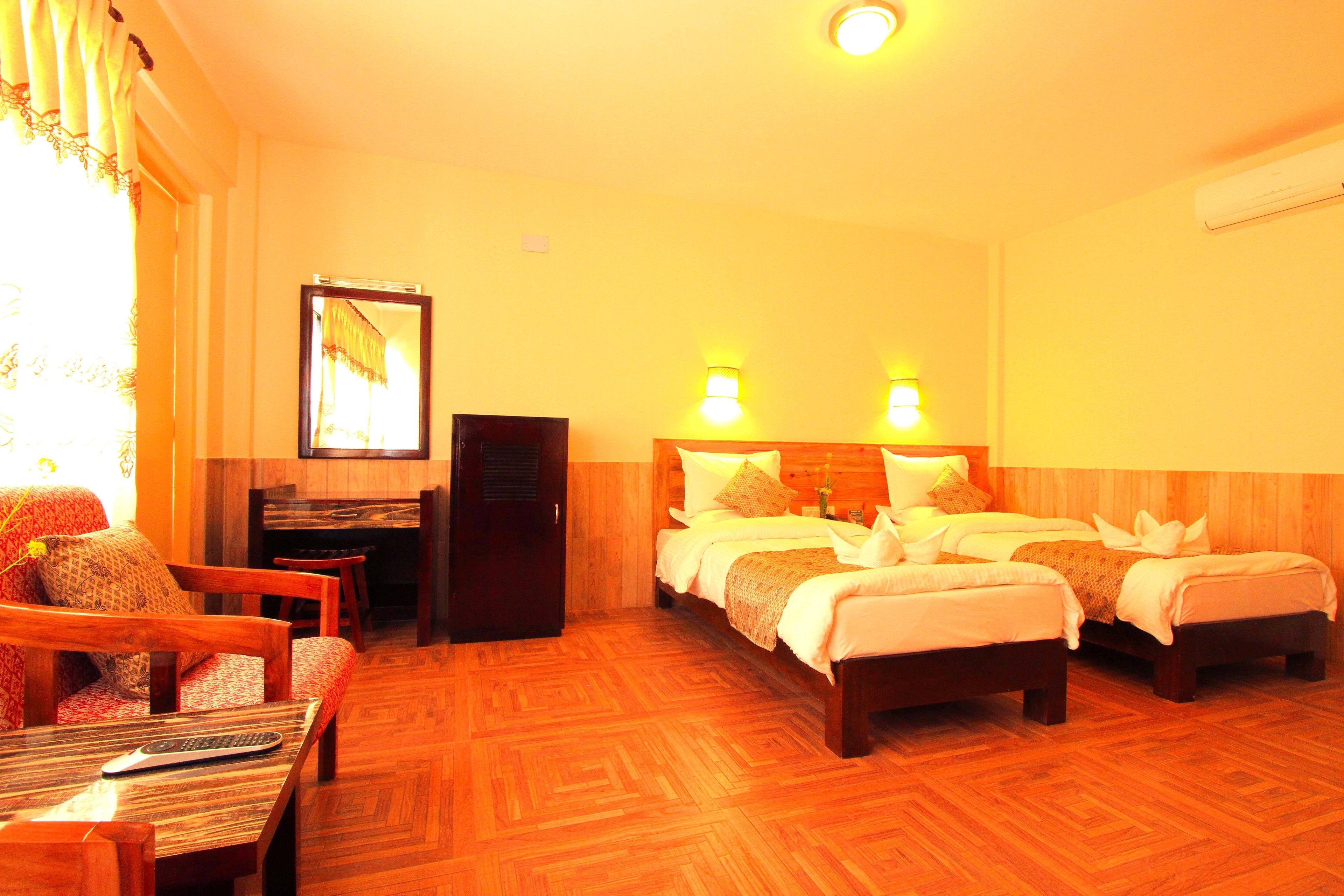 A hotel room with two beds, a sofa, a desk, and a mirror.