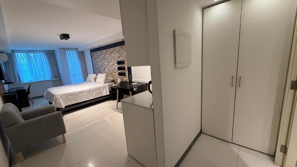 Camera d'hotel con un letto, una scrivania, una sedia, un armadio e un parete decorata in pietra.