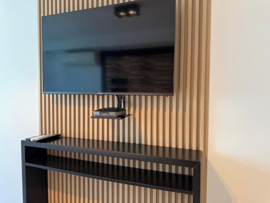 A flat-screen TV mounted on a wall with a wooden panel design.
