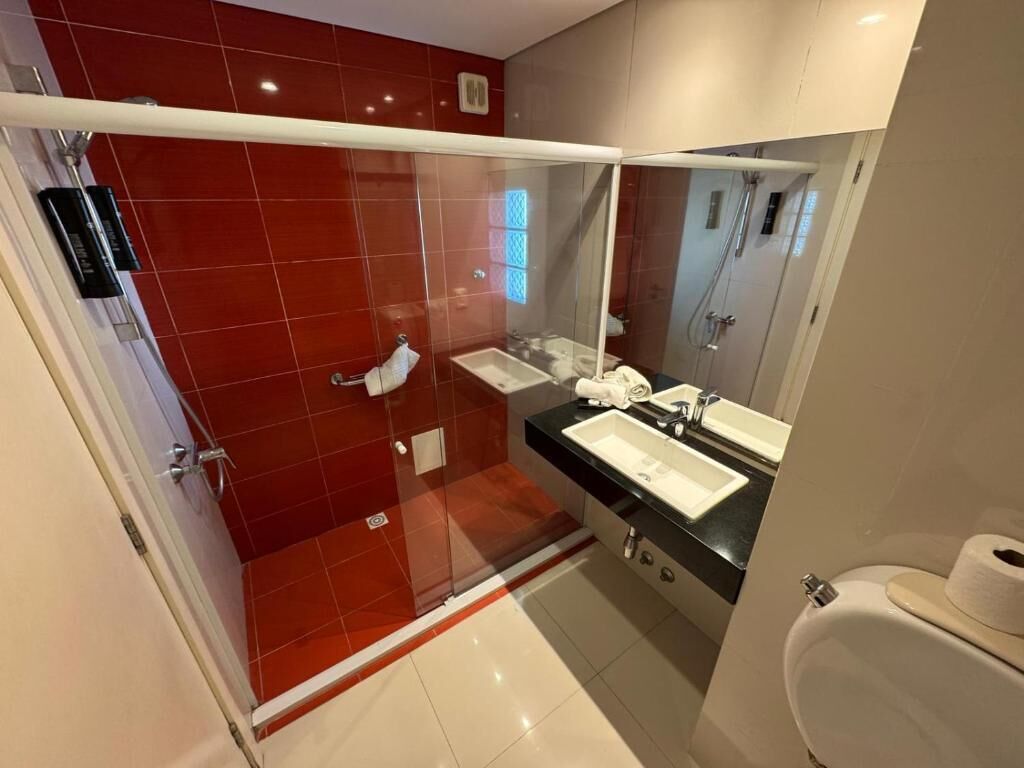 Un baño moderno con cabina de ducha de vidrio, lavamanos doble y un espejo grande.