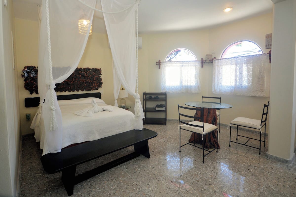 A bedroom with a bed, a bench, a table, and two chairs.
