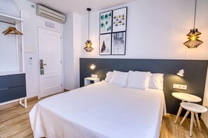 Una habitación de hotel moderna con una cama grande, mesitas de noche, un armario y obras de arte en las paredes.