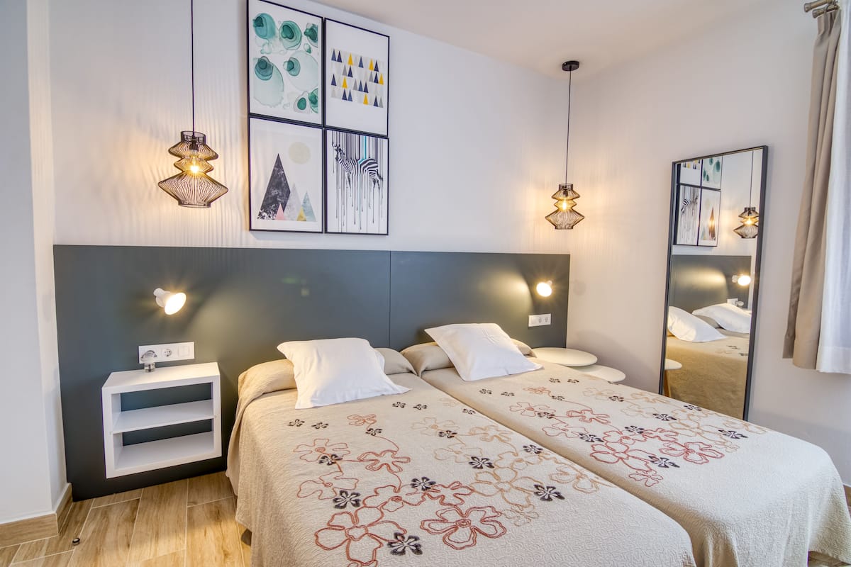 A double bed with floral bedding, bedside tables, wall art, and a mirror.