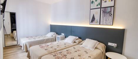 Una habitación de hotel con dos camas, una mesita y un espejo.
