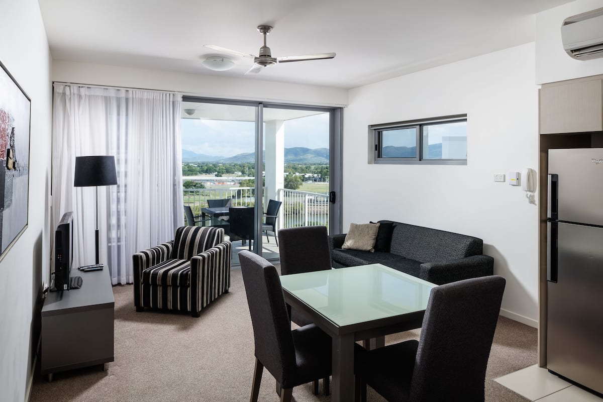 Une chambre d’hôtel moderne dotée d’un balcon, d’un coin repas, d’un canapé et d’une télévision à écran plat.
