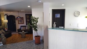 A reception area with a potted plant, a clock, and a closed door sign. - Hotel Villa Del Sol (Guadalajara)