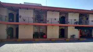 A building with multiple balconies, each with potted plants. - Hotel Villa Del Sol (Guadalajara)