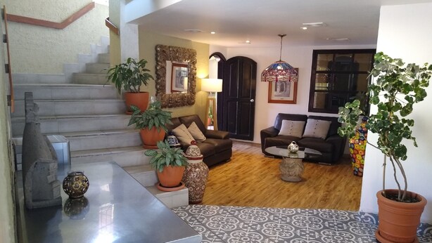 A spacious living area with a staircase, a sofa set, and potted plants. - Hotel Villa Del Sol (Guadalajara)