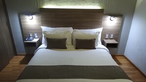 A modern hotel room with a large bed, two bedside tables, and a wooden headboard. - Hotel Villa Del Sol (Guadalajara)