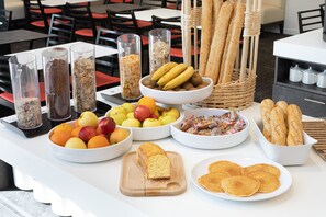 Een buffet met diverse soorten eten, waaronder fruit, brood en gebak.