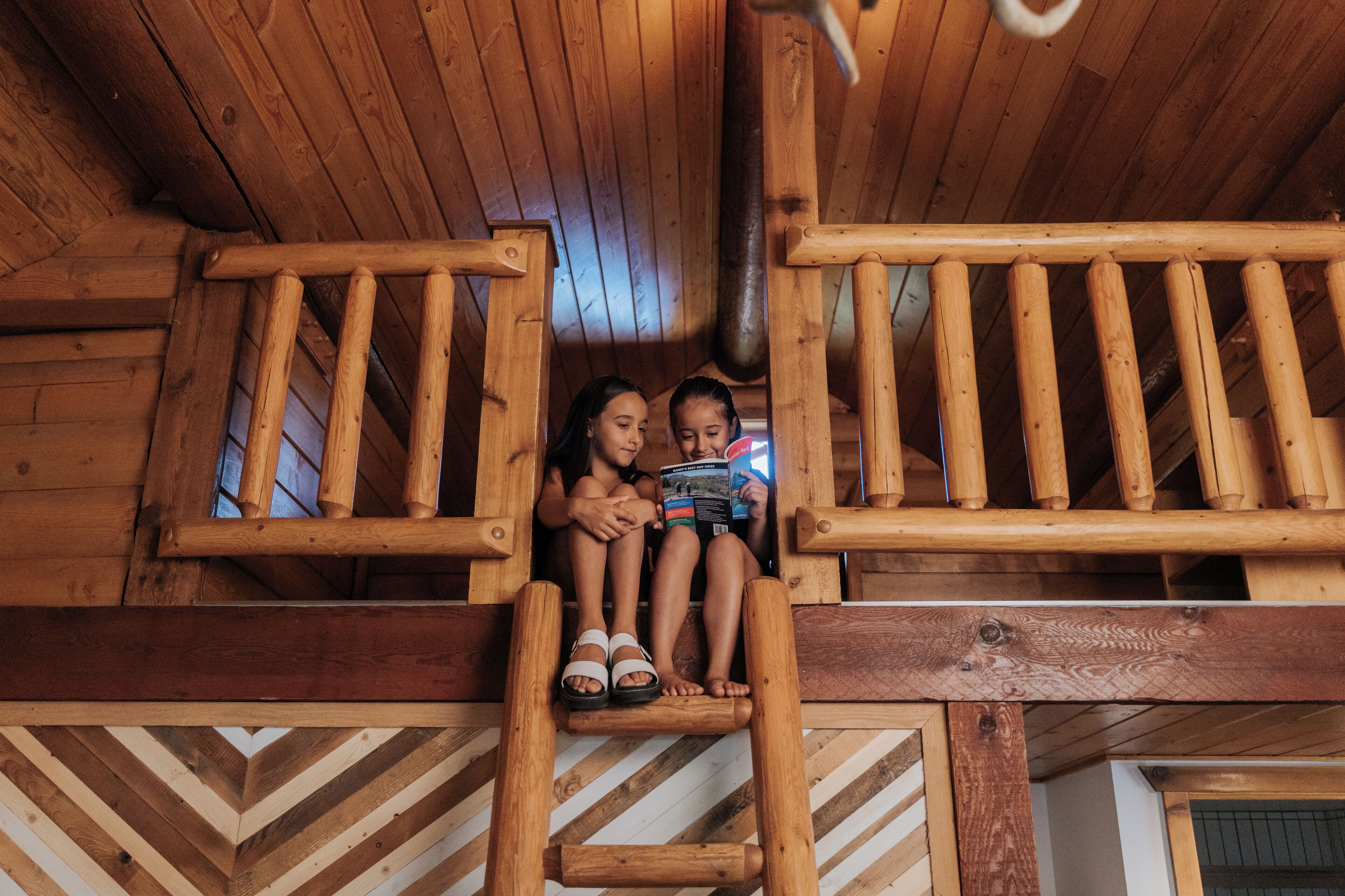 Un balcon en bois avec des balustrades, une échelle en bois et un plancher à motifs en chevrons.