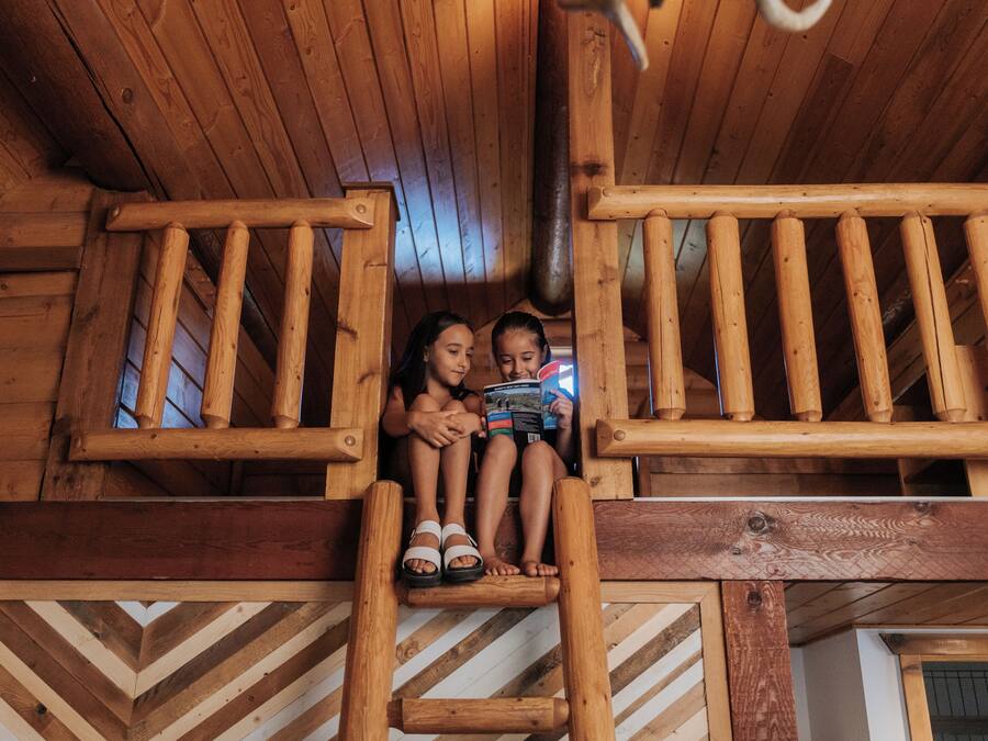 Un balcon en bois avec des balustrades, une échelle en bois et un plancher à motifs en chevrons.