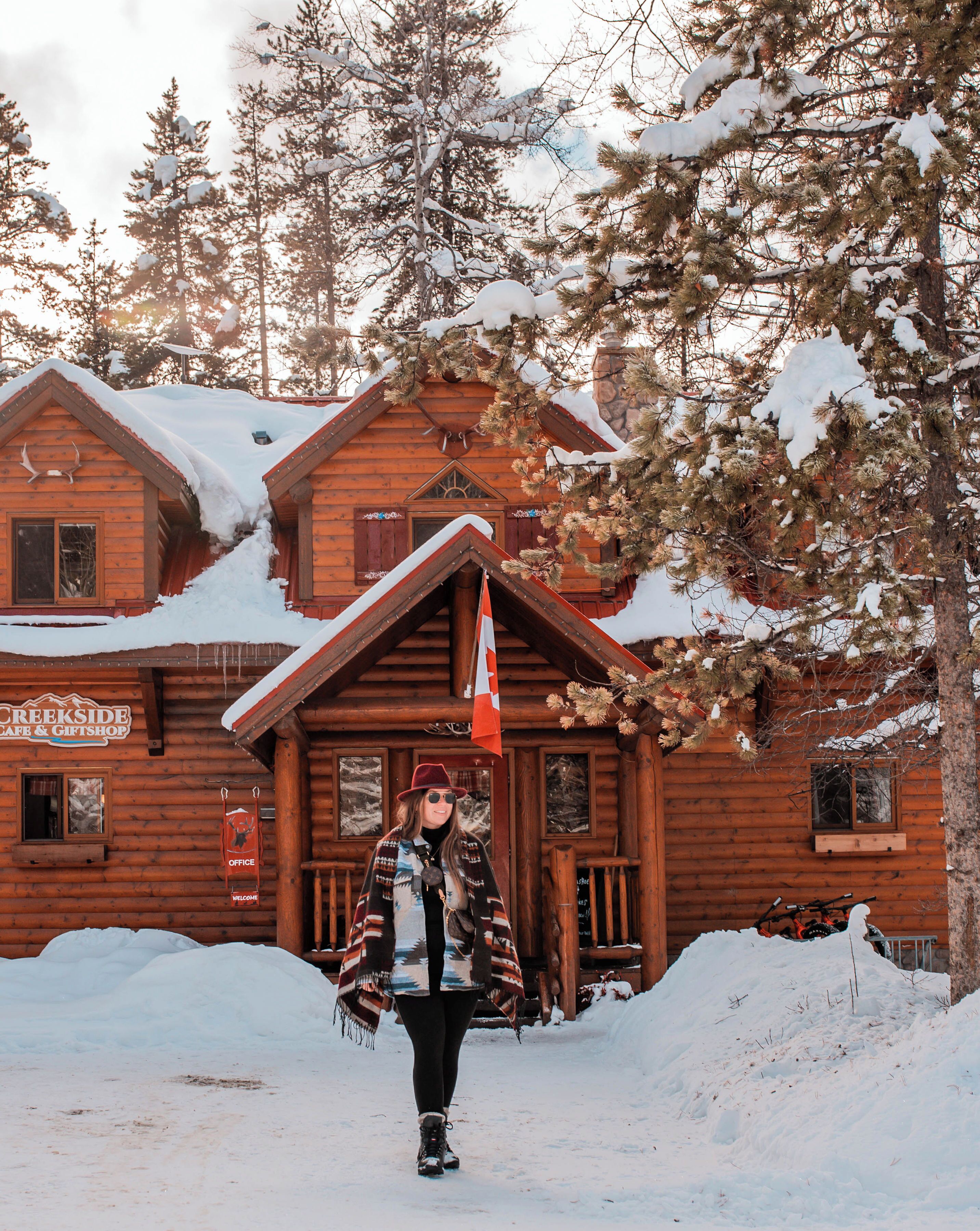 A wooden cabin with a porch, a flag, and a sign that reads 'CREEKSIDE GIFT SHOP.'