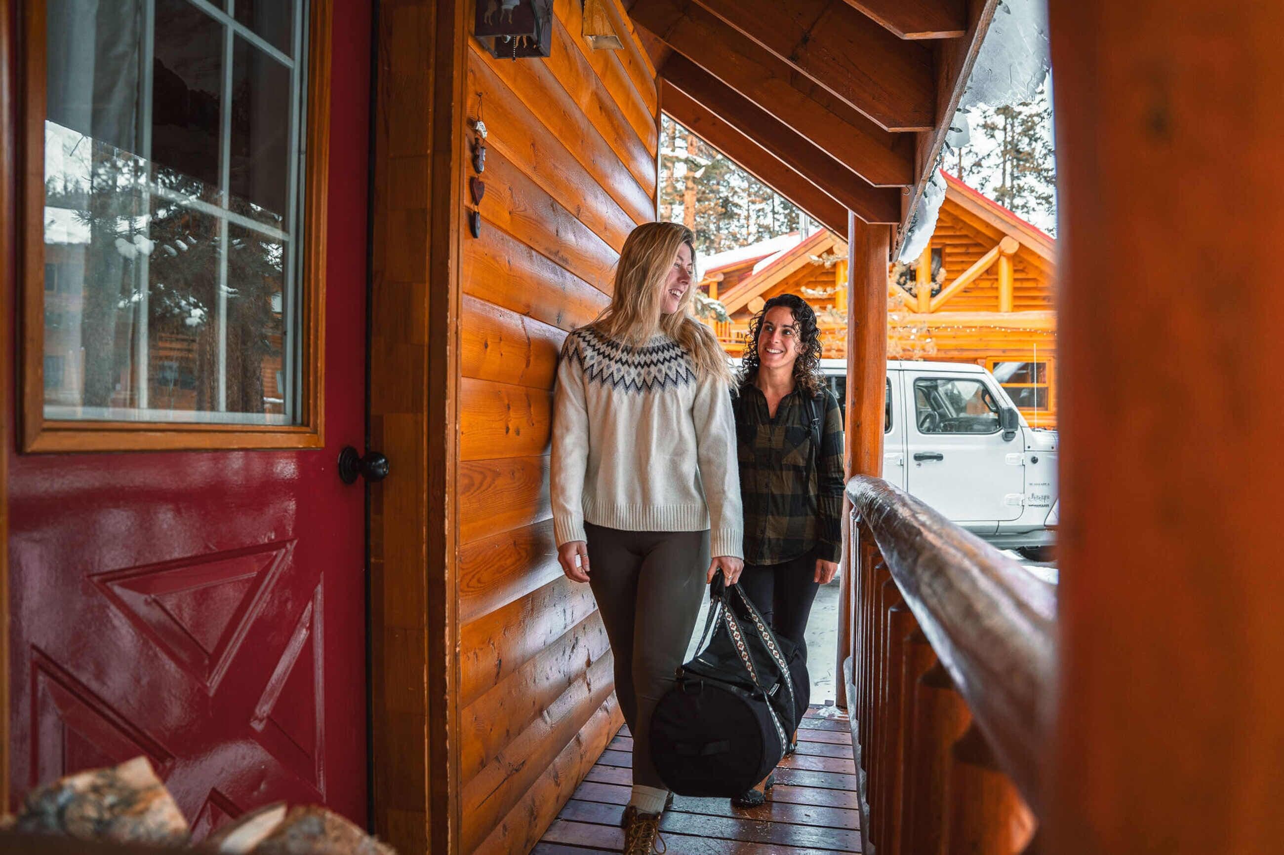 A wooden cabin with a red door and a wooden porch.