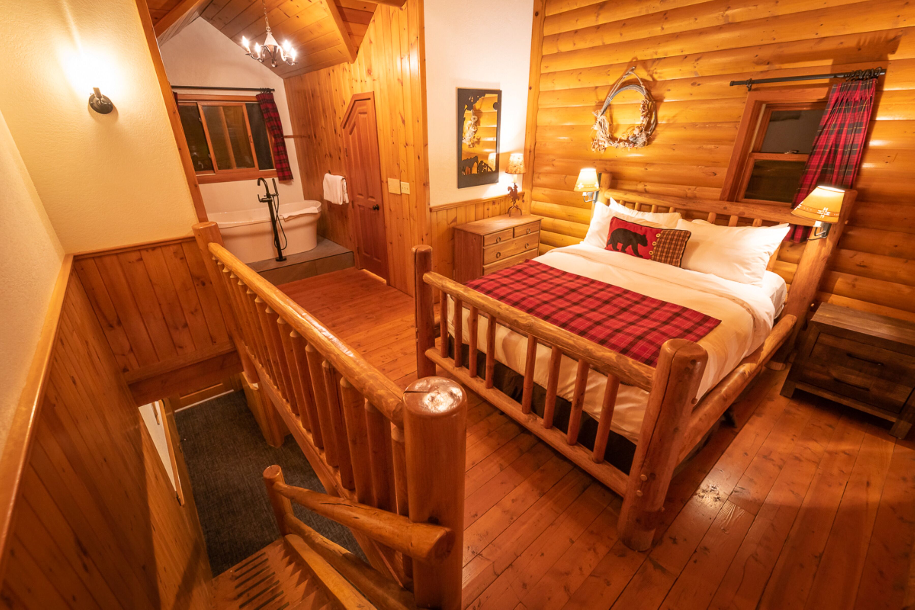 Une chambre dans une cabane en bois, avec un lit, une commode et une petite fenêtre avec des rideaux.