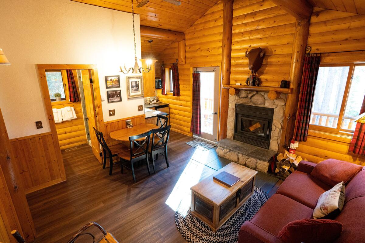 L’intérieur d’une cabane en rondins comprend un coin repas, une cheminée et un salon confortable.