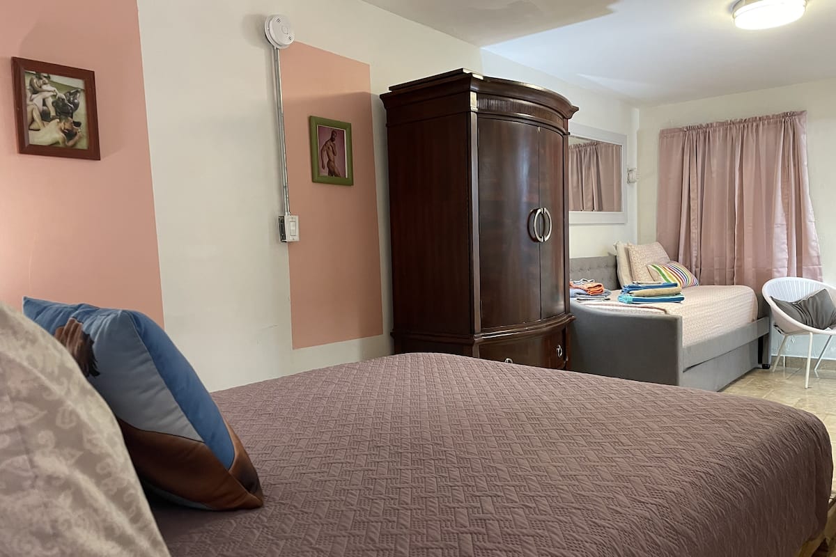 A bedroom with a large bed, a wardrobe, a desk, and a chair.