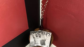 A corner with a red wall, a black wall, and a wooden object with a bottle and a string of white beads.