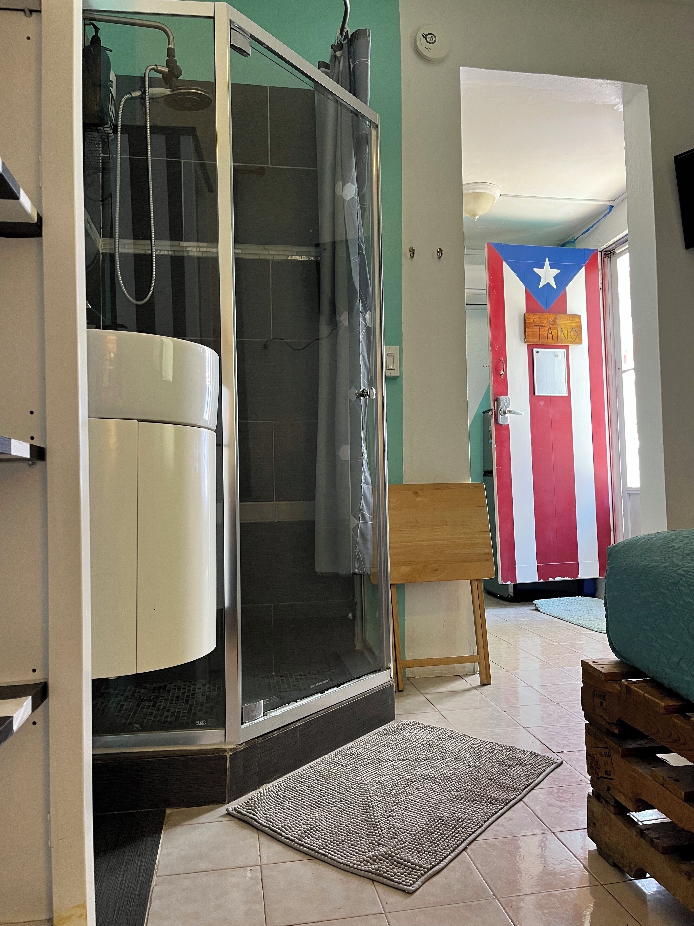 A room with a shower enclosure, a door with a flag design, and a wooden bench.
