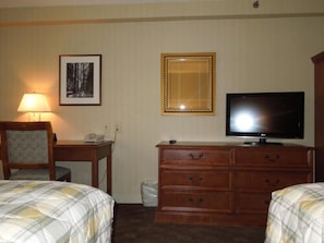 Habitació d'hotel amb dos llits, televisió, escriptori amb làmpada i mirall.