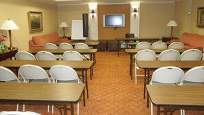 Een vergaderzaal met tafels, stoelen, een televisie en een whiteboard.
