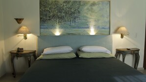 A bedroom with a bed, two bedside tables, two wall-mounted lamps, and a painting above the bed. - Casa Madonna La Providence Hotel Boutique (Guadalajara)