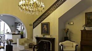 A spacious living area with a chandelier, a fireplace, a framed portrait, and a piano. - Casa Madonna La Providence Hotel Boutique (Guadalajara)