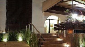 A staircase leading to an entrance with a wooden handrail, surrounded by tall grass and a potted plant. - Casa Madonna La Providence Hotel Boutique (Guadalajara)