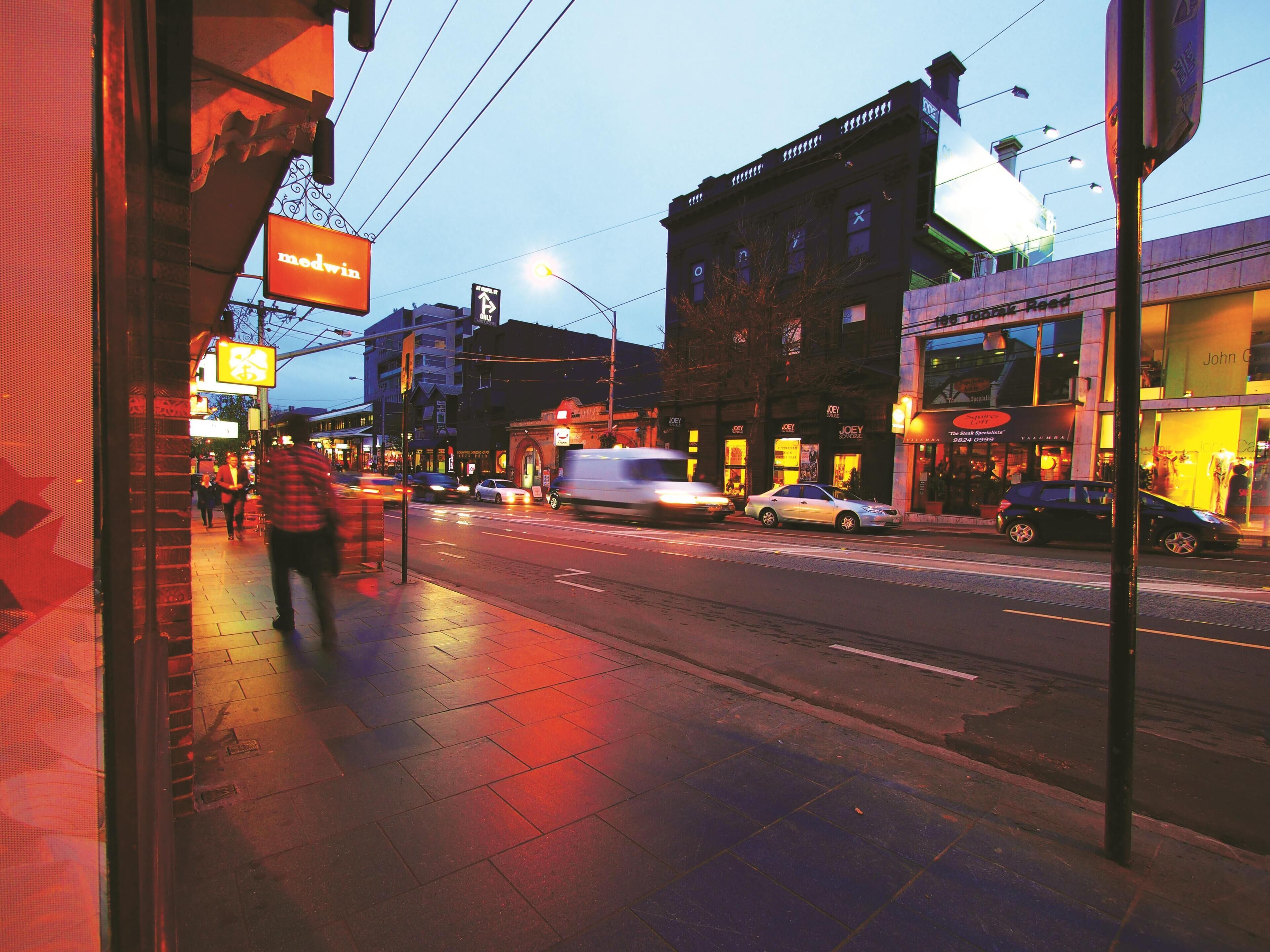A street view with a building labeled 'JOEY SOONER' and a 'John G' sign.