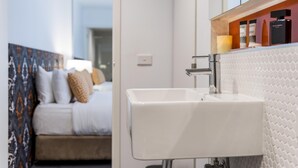 A modern hotel room with a bed, a white sink, and a mirror. - Oaks Melbourne South Yarra Suites (South Yarra)