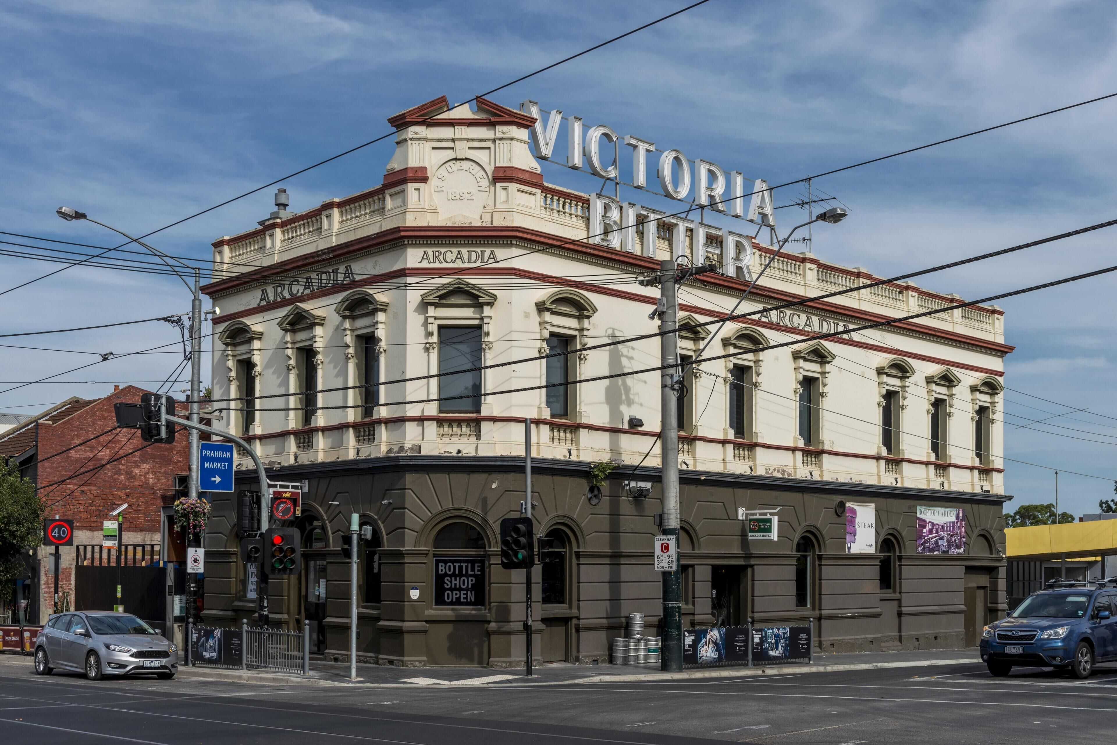 En historisk byggnad med skylten ”VICTORIA BIERER”, ordet ”ARCADIA” på fasaden och en skylt som visar att butiken är öppen: ”BOTTLE SHOP OPEN”.