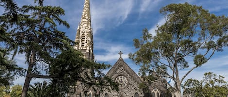 Una iglesia con una aguja alta, ventanas arqueadas y una torre con reloj.