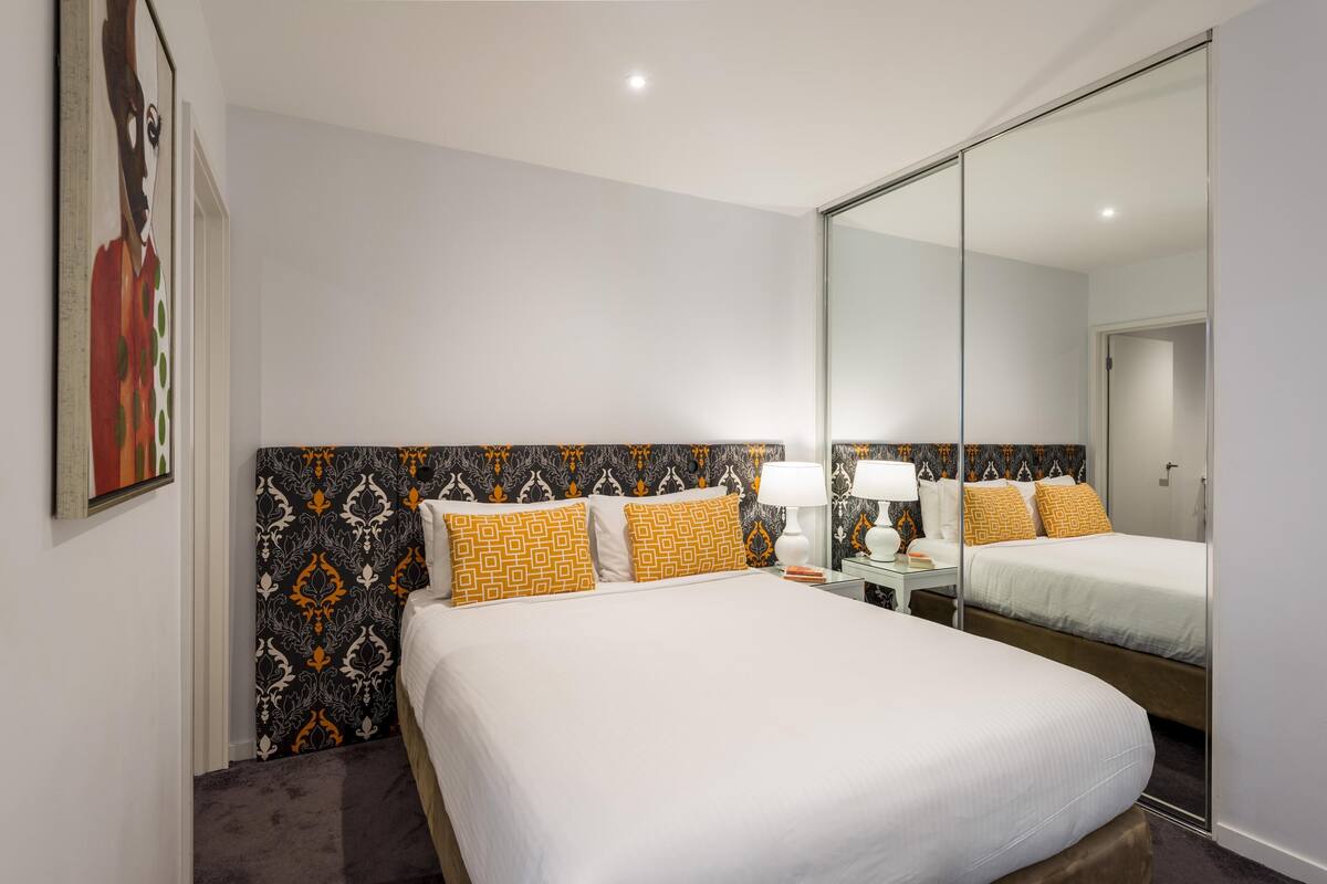 A hotel room with a large bed, a mirror, and a wardrobe.