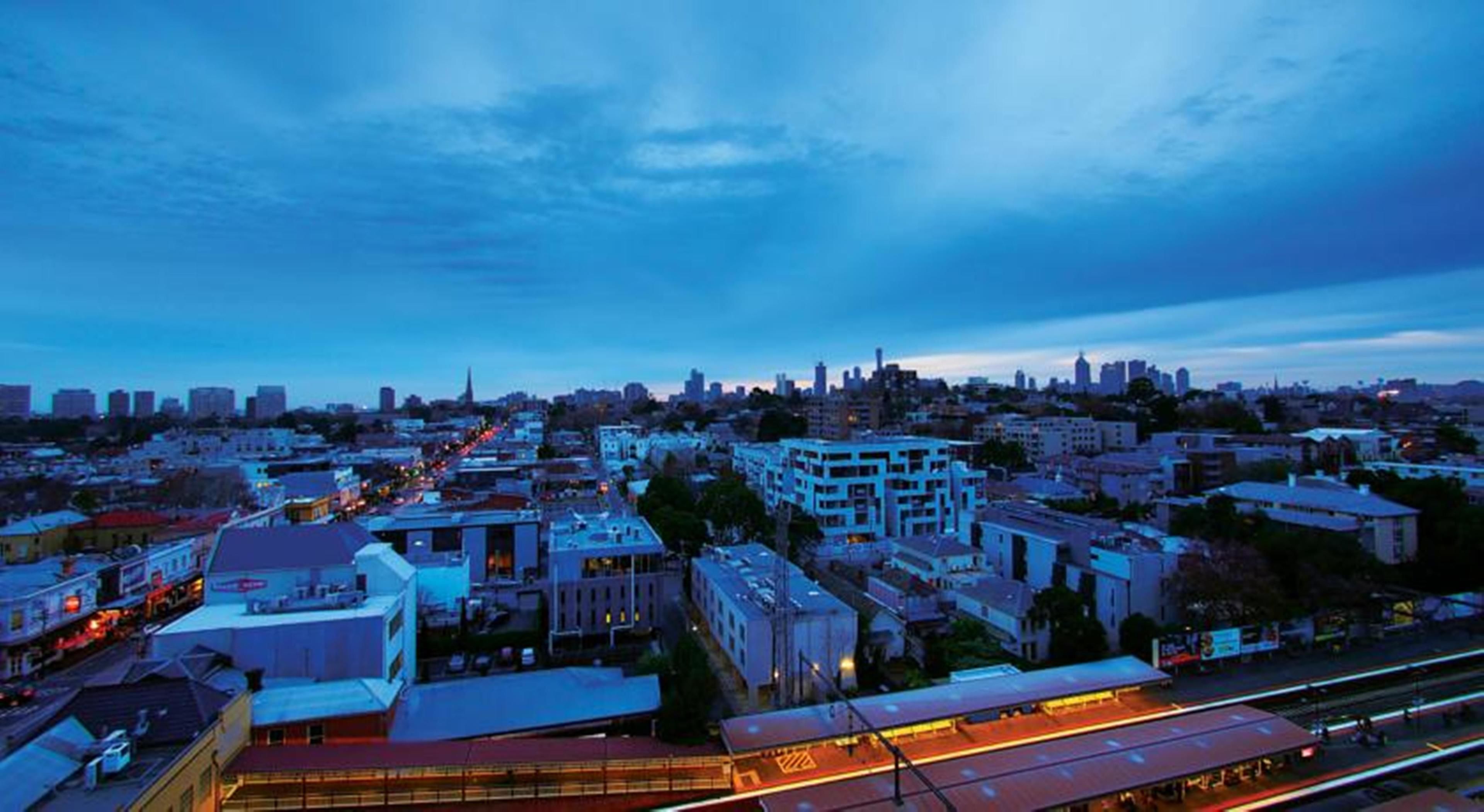 A cityscape at dusk with a prominent building in the foreground and a distant skyline.