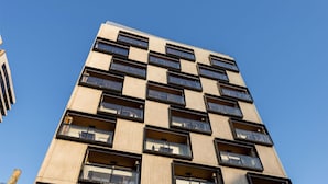Un edificio de varios pisos con un diseño moderno, que cuenta con amplios ventanales y balcones.