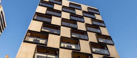 Un edificio de varios pisos con un diseño moderno, que cuenta con amplios ventanales y balcones.