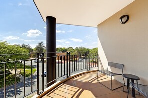 Un balcón con barandilla curva, una mesa y una silla.