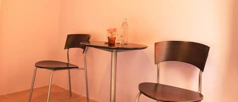 Habitación de esquina con dos sillones, una mesita pequeña, una botella y un florero.