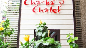Letrero de Cha-ba Chalet con escritura tailandesa y un diseño floral.