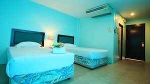 Habitación de hotel con dos camas, una mesita de noche con lámpara y un equipo de aire acondicionado.