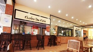 Una cafetería con mesas y sillas de madera, una barra con un menú y un letrero que dice "Chaba De Café".