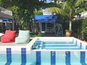 A swimming pool with blue-tiled edges, surrounded by greenery and a white fence. - Zea Za Bungalow (Hua Hin)